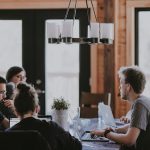 A group of people collaborating at a table, each using laptops to discuss request for information software.